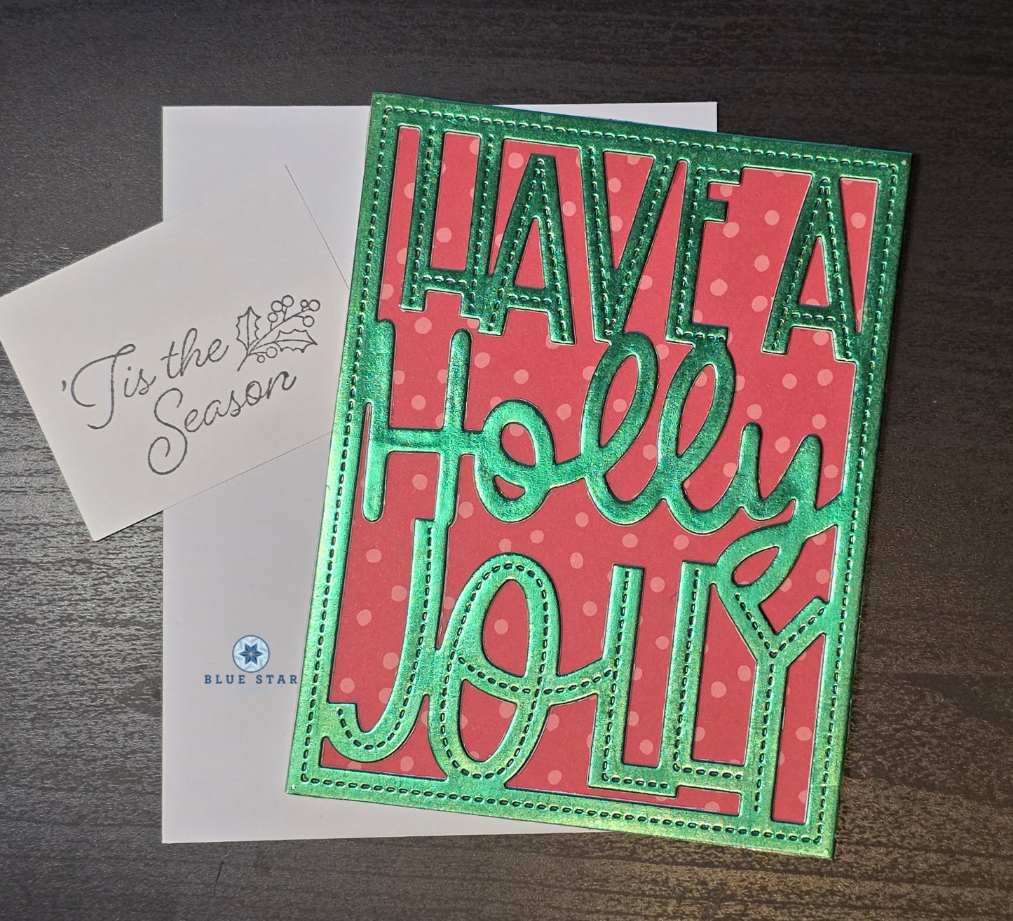 Christmas card with 'Have a Holly Jolly' text on a red background, featuring a white envelope.