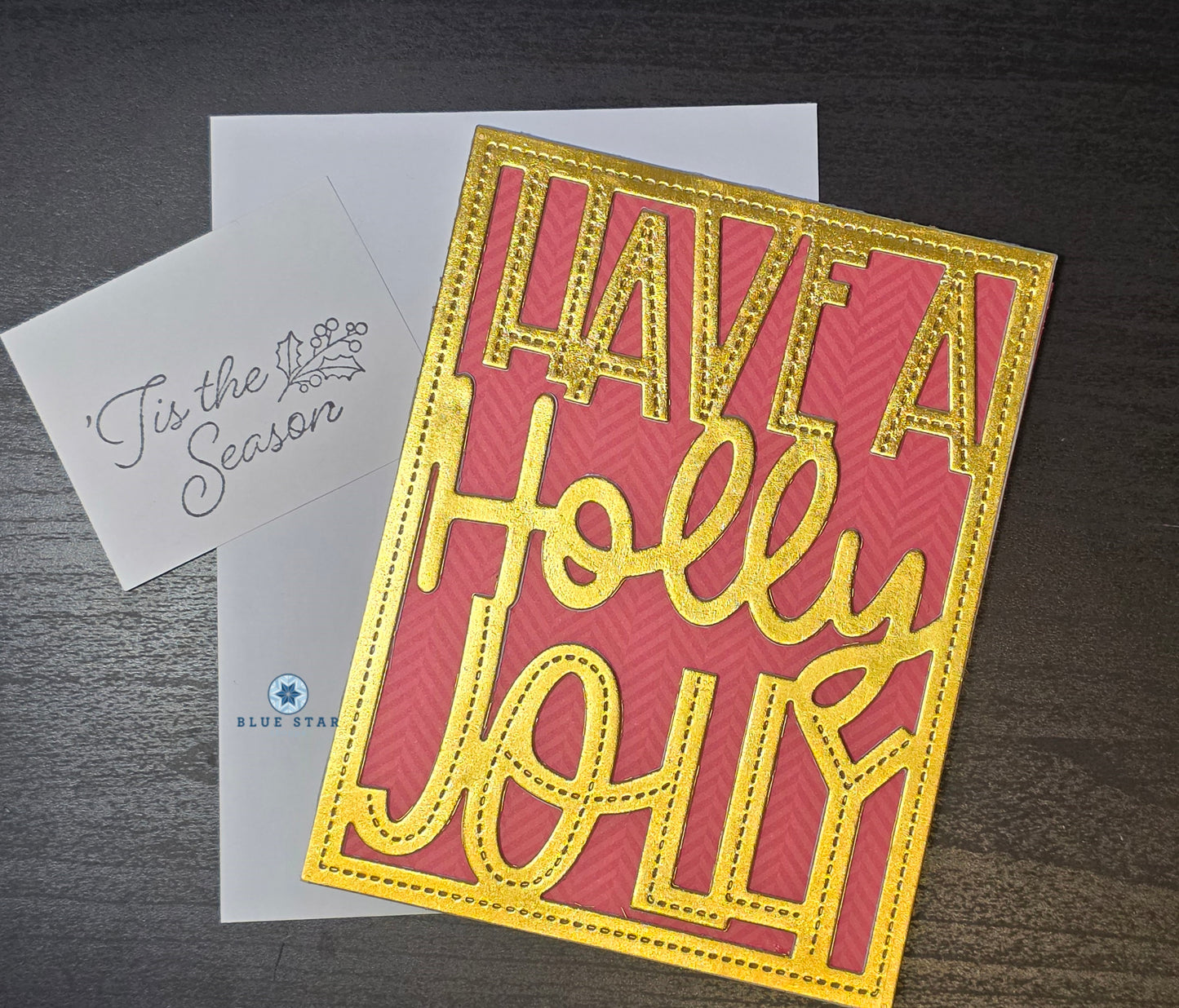 Holiday card with 'Have a Holly Jolly' text on a red surface